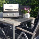 Barbacoa InfraBeam - Beefeater sobre una mesa en un jardín, lista para su uso.