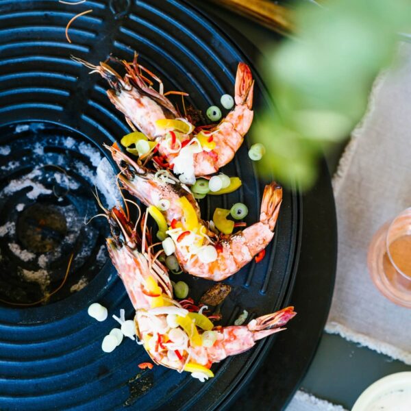 Camarones cocinándose en la barbacoa de mesa Tabl’O con guarnición de cebollines y pimientos.