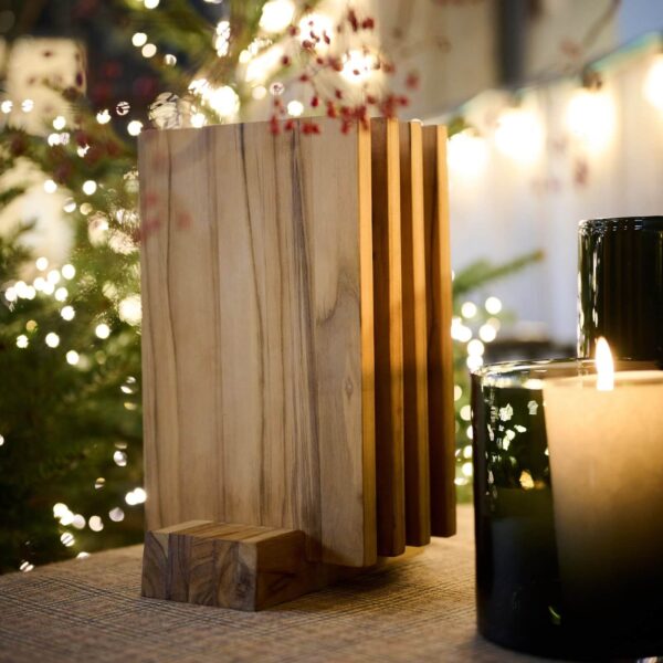 Set de tablas de cortar de madera de teca con soporte junto a velas decorativas