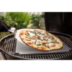 Pizza con espárragos y jamón serrano siendo cocinada en la barbacoa de carbón Weber Master-Touch de 67 cm.