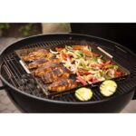 Pollo asado y vegetales variados cocinándose en la barbacoa de carbón Weber Master-Touch de 67 cm.