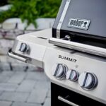 Primer plano de los mandos de control y el logo de la barbacoa de gas Weber Summit FS38 E, mostrando su diseño elegante y funcional.