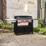 Plancha Weber SLATE GPSB 76 cm Premium ubicada en un patio, con diseño elegante y funcional, tapa cerrada y almacenamiento integrado.