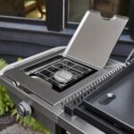Detalle del quemador lateral de la Plancha Weber SLATE GPSB 76 cm Premium, con tapa abierta y diseño funcional para acompañamientos.