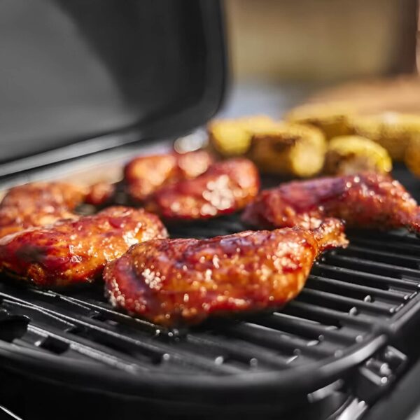 Primer plano de pollo asado cocinándose en la barbacoa Weber Traveler® Compact.