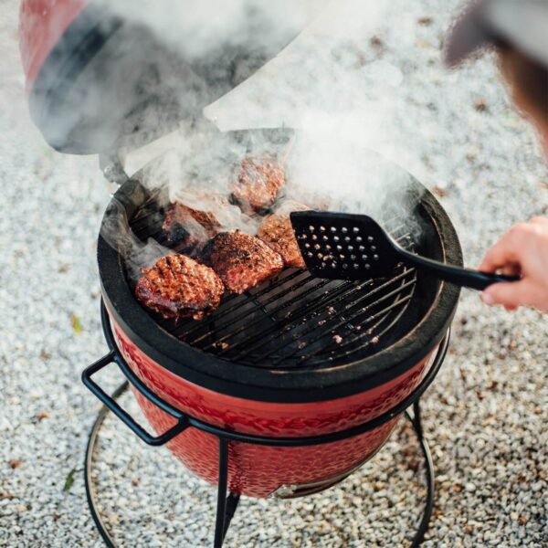 Hamburguesas cocinándose en la parrilla Kamado Joe Jr. al aire libre.