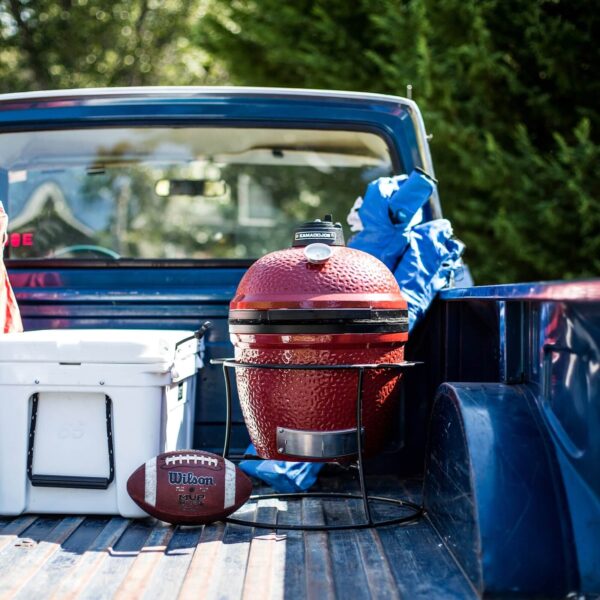 Kamado Joe Jr. colocado en la parte trasera de una camioneta junto a una nevera y un balón de fútbol americano.