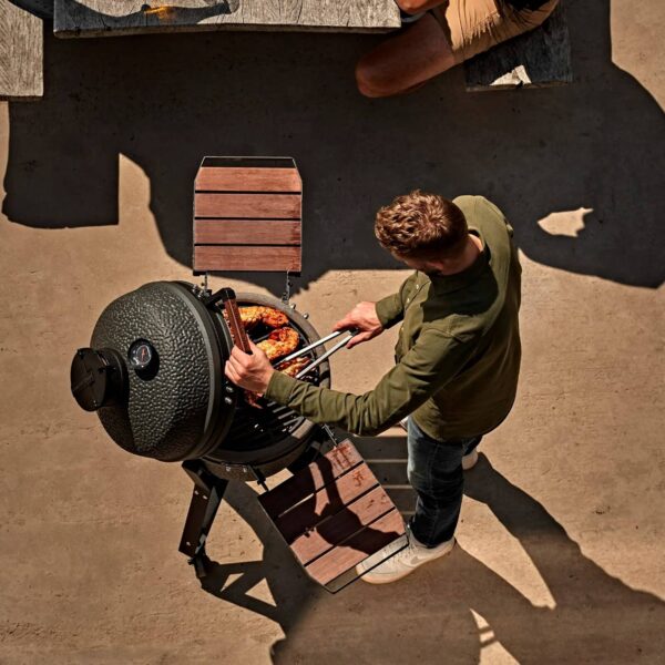 Personas disfrutando de una parrillada en el Kamado VX Medium durante una reunión al aire libre.