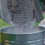 Vaciado de cenizas de la Caja Portátil de Cocción Lateral CharGriller en un cubo de metal.