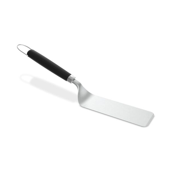 Espátula de acero inoxidable flexible con mango negro antideslizante y diseño ergonómico, ideal para cocinar en planchas, parrillas y sartenes.