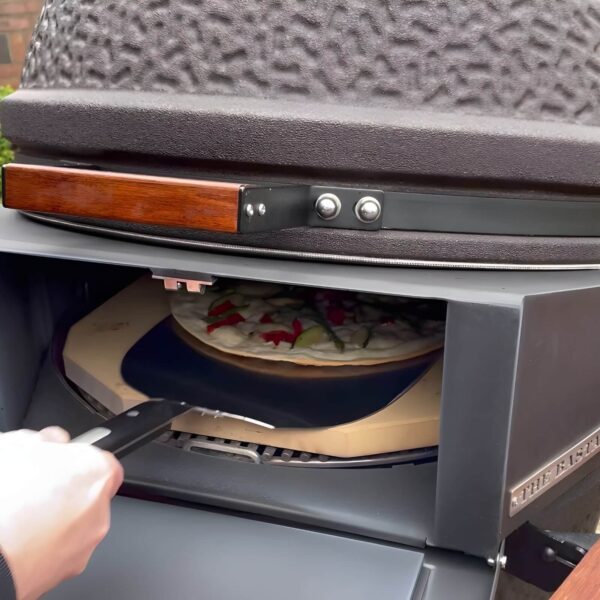 Mano colocando una pizza con pala de acero inoxidable en horno The Bastard.