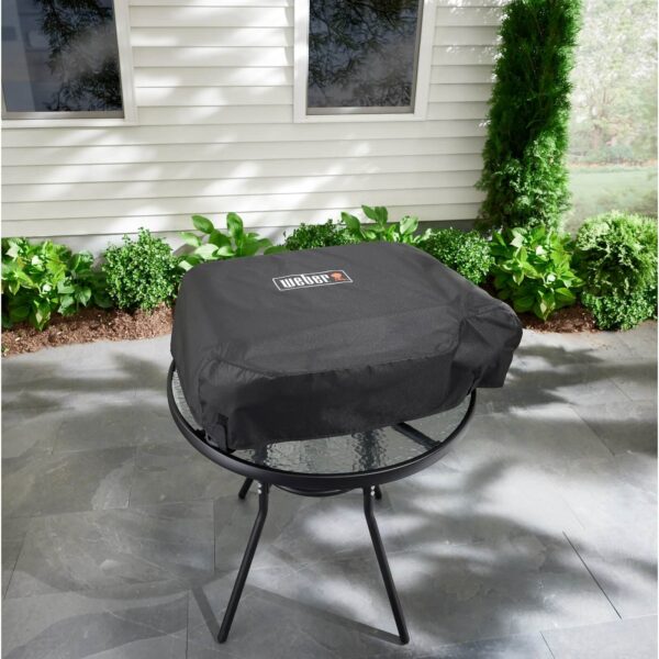 Funda Premium Weber SLATE GP 56 cm colocada sobre una mesa en un espacio al aire libre.