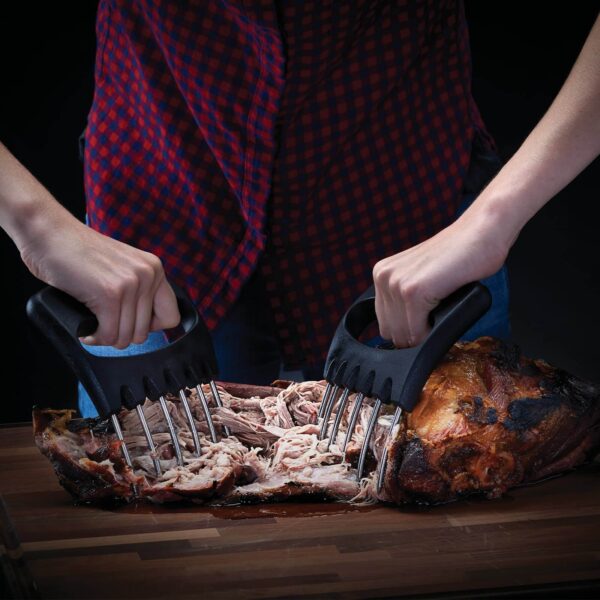 Persona utilizando garras para desmenuzar carne sobre una tabla de cortar.