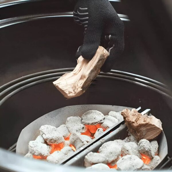 Mano con guante colocando carbón en una barbacoa con cestas Char-Basket de Weber