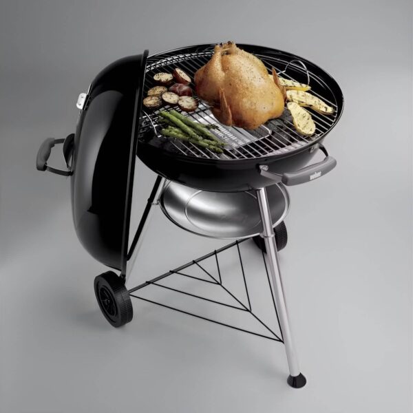 Barbacoa de carbón Weber Compact Kettle Ø 57 cm con pollo asado, espárragos y verduras a la parrilla.