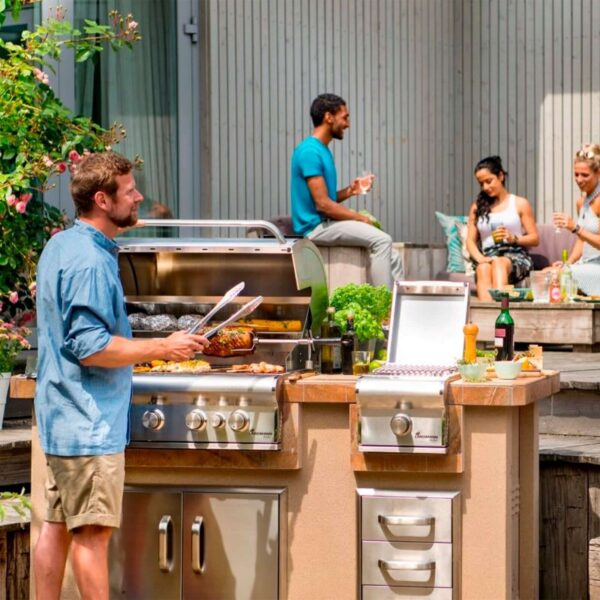 Hombre cocinando en la barbacoa de gas Ardor PTS 5.0 durante una reunión con amigos en un jardín.