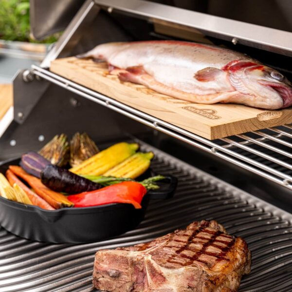 Parrillada activa en la barbacoa Napoleon Serie 500 32 con variedad de alimentos como pescado, carne y vegetales.