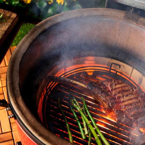 Interior de la Kamado Big Joe III con carne y espárragos asándose.