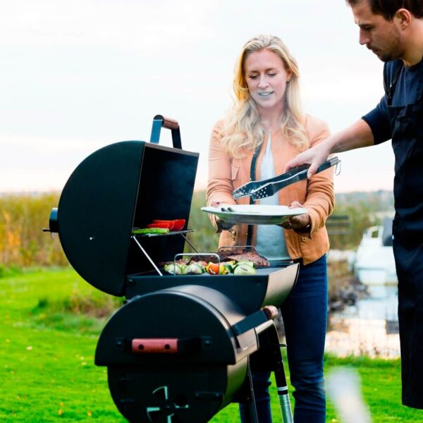 Pareja disfrutando de una agradable tarde de barbacoa con la Black Taurus 660+, que muestra su amplia capacidad de cocción.