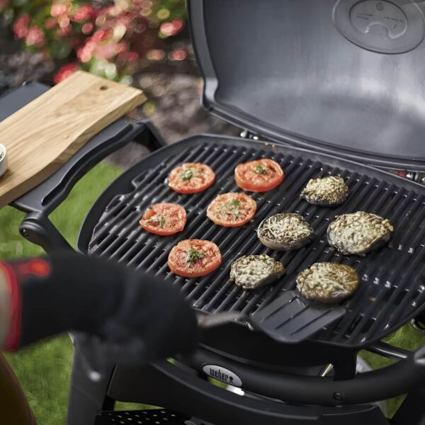 Verduras asándose en la barbacoa Weber Q 2200, incluyendo rodajas de tomate y champiñones.