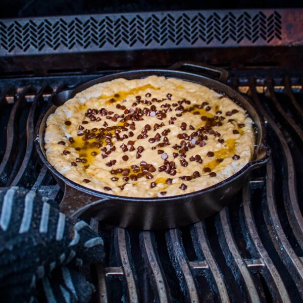 Dulce de masa dorada con chispas de chocolate en una sartén de hierro fundido sobre la parrilla, cocinándose hasta alcanzar la perfección.