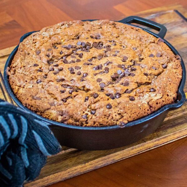 Pastel de chocolate con chispas recién horneado en una sartén de hierro fundido, sobre una tabla de madera.