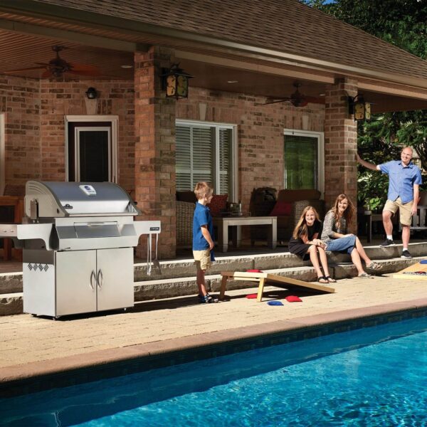 Familia disfrutando del día junto a la piscina con la Barbacoa de Carbón Profesional Napoleon en el patio.