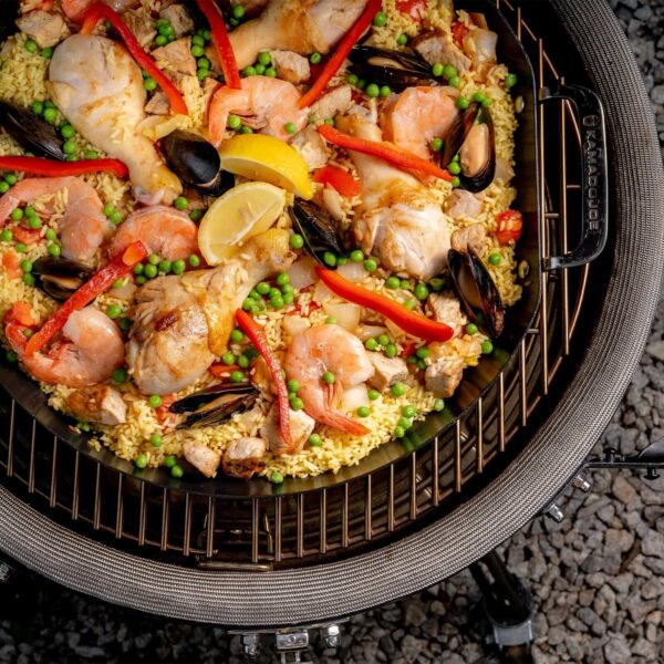 Paella de mariscos y pollo cocinándose en una paellera Kamado Joe vista desde arriba.