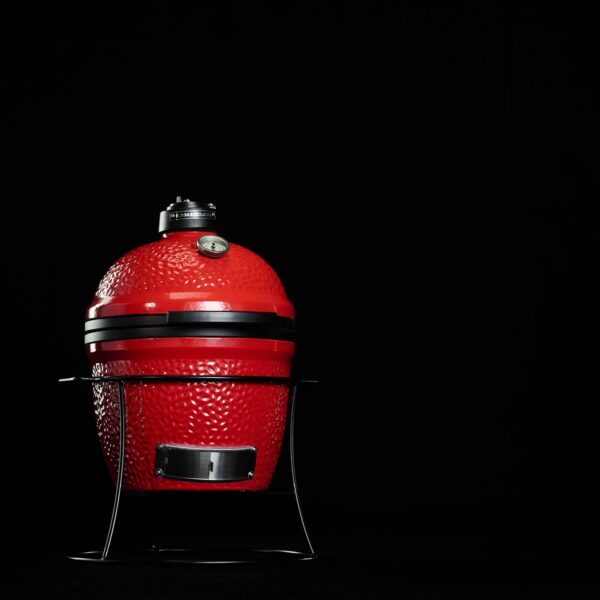 Kamado Joe Jr. en rojo, destacado sobre un fondo negro, mostrando su diseño robusto y compacto.