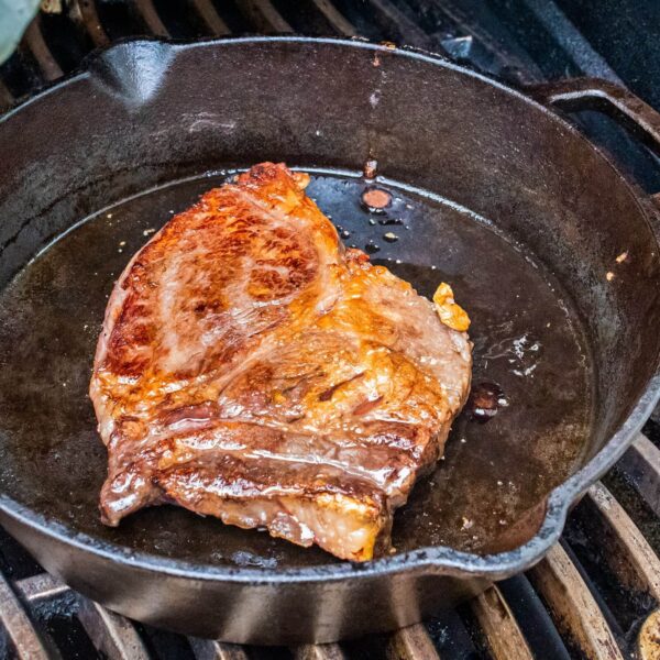 Filete jugoso con una corteza perfectamente dorada en una sartén de hierro fundido sobre la parrilla.