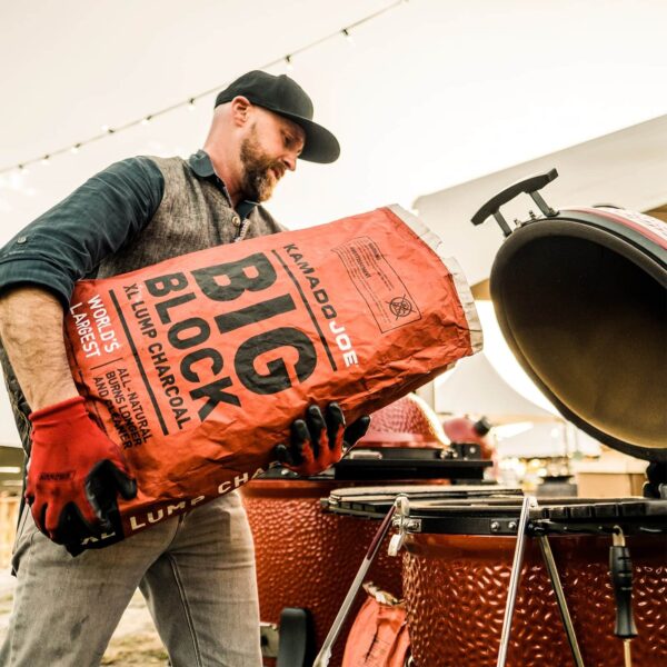 Un asador prepara su parrilla Kamado Joe con un nuevo saco de carbón Big Block.