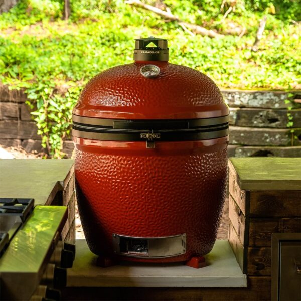 Barbacoa Kamado Big Joe III Stand-Alone de color rojo instalada en una cocina de exterior.