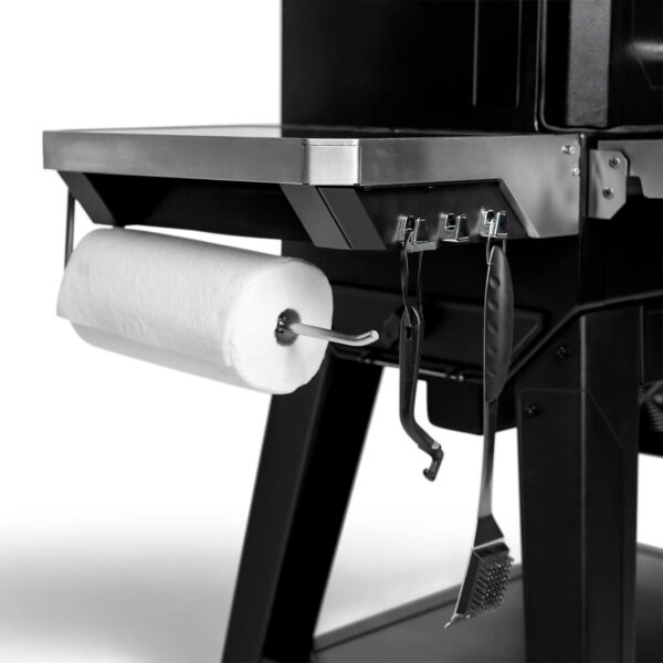 Vista lateral de la Barbacoa Gravity Series XT de Masterbuilt, mostrando un soporte para toallas de papel y ganchos para herramientas de cocina.