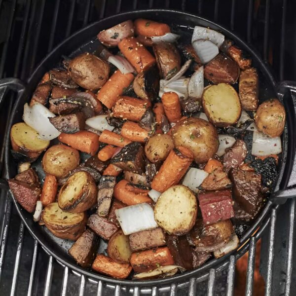 Plancha Redonda GBS de Acero Fundido Weber cocinando vegetales y carne en una barbacoa.