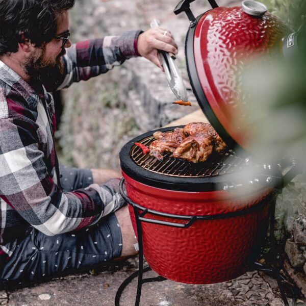 Hombre cocinando pollo asado en el Kamado Joe Jr. en un entorno exterior.