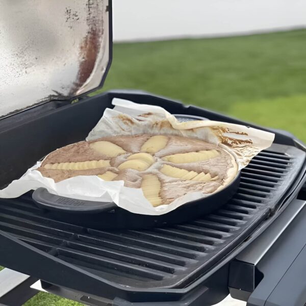 Plancha Redonda GBS de Acero Fundido Weber cocinando un pastel de pera en una barbacoa.