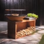Asador moderno con anillo para parrilla y espacio de almacenamiento de leña en un patio exterior