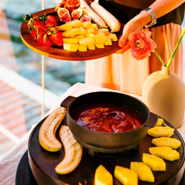 Plato con fresas, piña, higos y plátanos junto a una cazuela de fondue de chocolate en la parrilla OFYR Tabl'O.