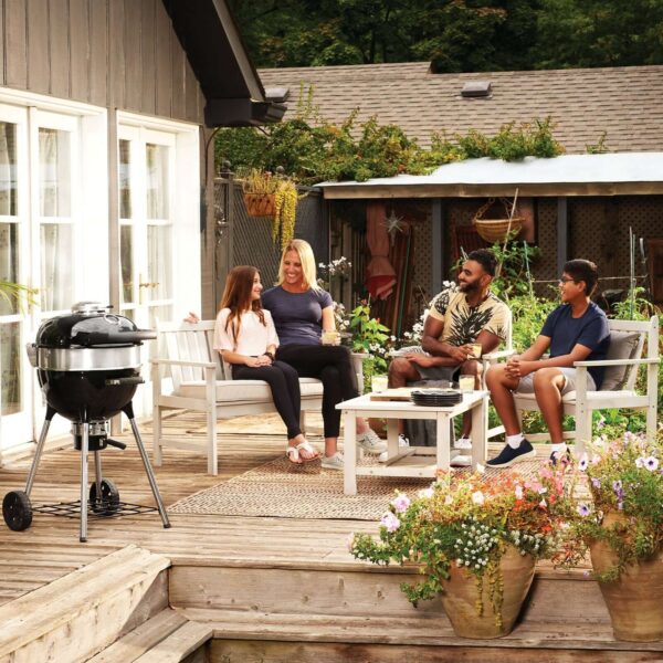 Familia disfrutando de un momento juntos en una terraza al aire libre con una barbacoa Pro Kettle 47 cm 2024 de Napoleon al lado