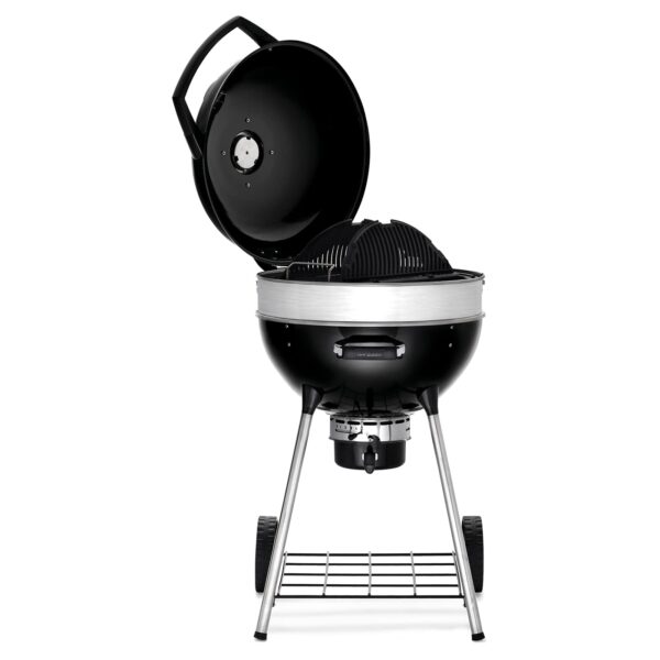 Barbacoa Pro Kettle de 57 cm abierta mostrando su interior con una rejilla ondulada de hierro fundido y la trampilla de carbón expuesta para facilitar la recarga, todo montado sobre un resistente marco con ruedas.