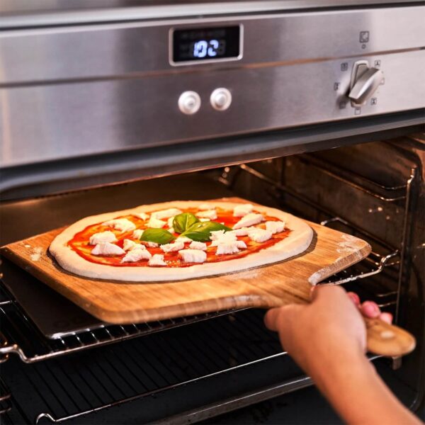 Pizza casera en una piedra de acero inoxidable Ooni dentro de un horno doméstico.