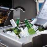 Botellas de cerveza en un compartimento de hielo integrado en la barbacoa.
