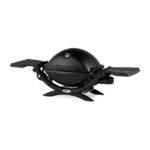 Barbacoa de gas Weber Q 1200 con tapa cerrada y mesas laterales plegables.
