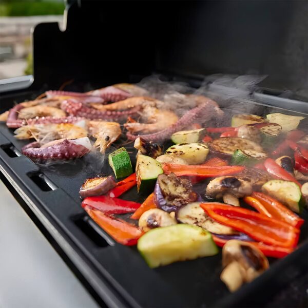 Mariscos y vegetales variados cocinándose a la plancha en la barbacoa Weber Summit FS38 E.