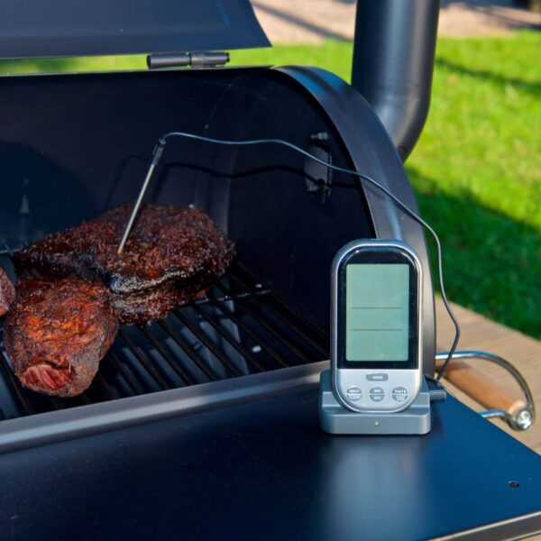 Termómetro digital Landmann junto a carne asada en una parrilla, indicando la temperatura precisa para un asado perfecto.