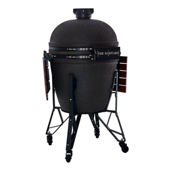 Kamado The Bastard con cuerpo de cerámica negra, sistema de bisagras reforzado y mesas laterales plegables de madera.