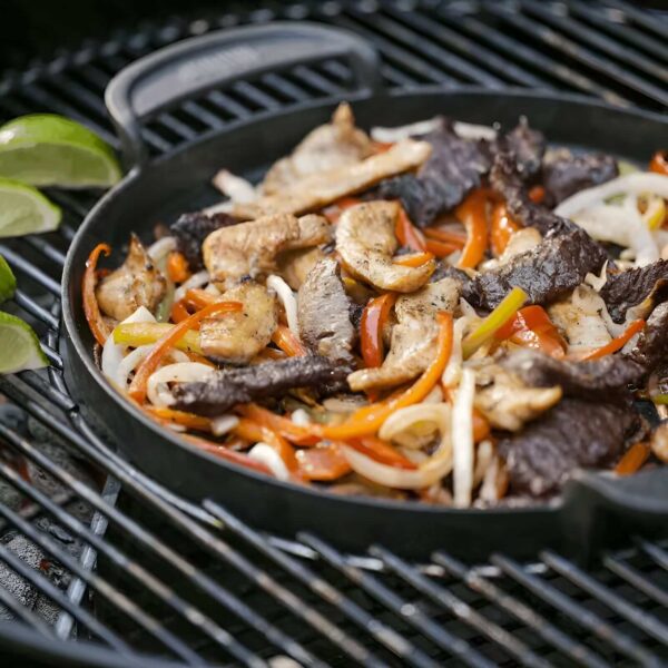 Plancha Redonda GBS de Acero Fundido Weber cocinando fajitas de carne y pollo en una barbacoa.