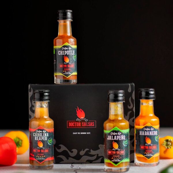 Pack de cuatro botellas de salsas picantes de 20 ml de Doctor Salsas, con una caja negra como fondo. En la imagen se ve una botella de Salsa de Chipotle sobre la caja y tres botellas de Salsa de Jalapeño, Salsa Habanero y Salsa Carolina Reaper en la parte inferior.