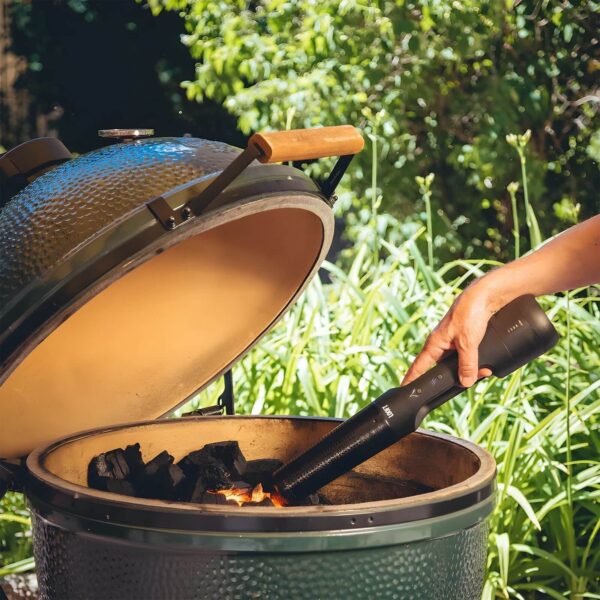 Mano encendiendo carbón en una barbacoa tipo Kamado con el encendedor eléctrico Looft Lighter X al aire libre.