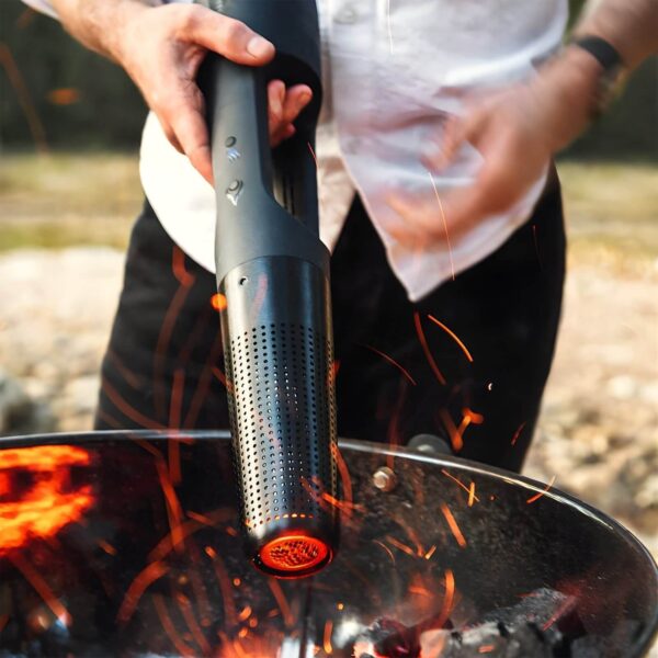 Persona encendiendo carbón en una parrilla con el encendedor eléctrico Looft Lighter X, generando chispas y llamas.